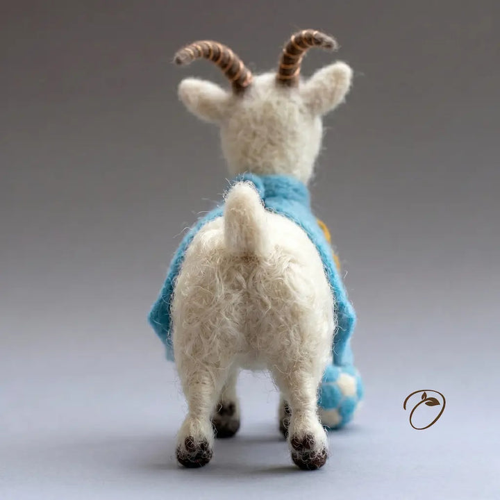 Toy goat with a blue sweater on a gray background