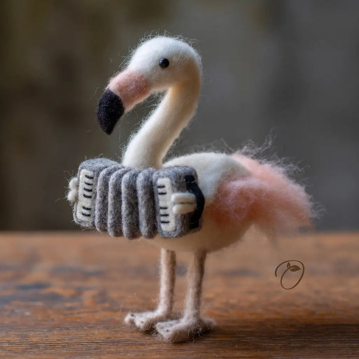Felted flamingo toy wearing a sweater on a wooden surface