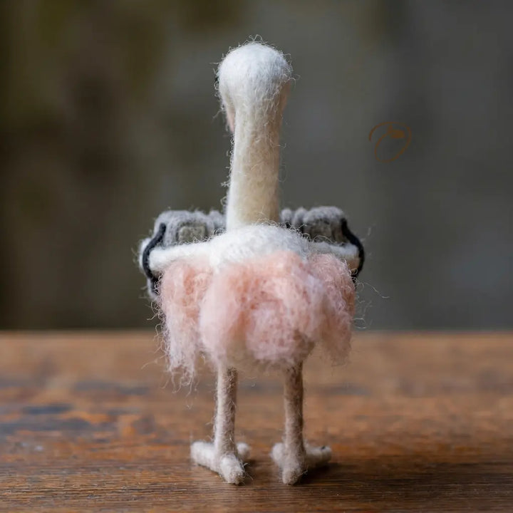 Small felted animal figurine on a wooden surface with a blurred background
