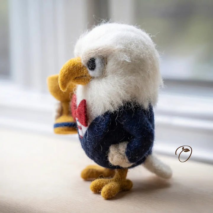 Felted eagle figurine with a heart design on a light surface.