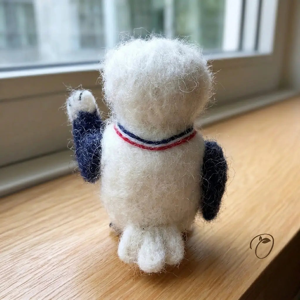 White plush toy with blue and red accents on a wooden surface