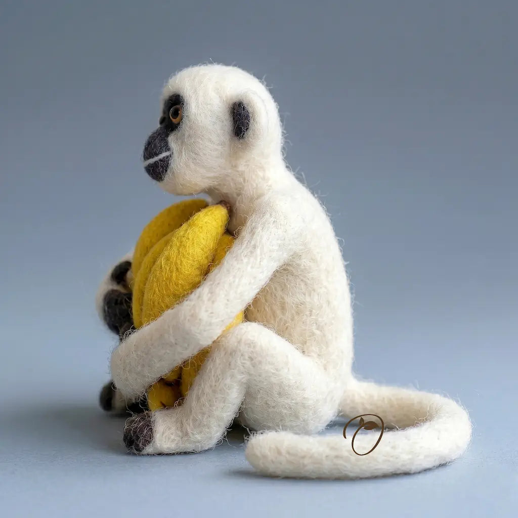 White monkey toy holding a yellow ball on a gray background