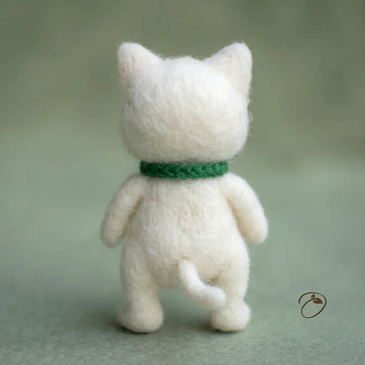 White cat figurine with a green collar on a light green background