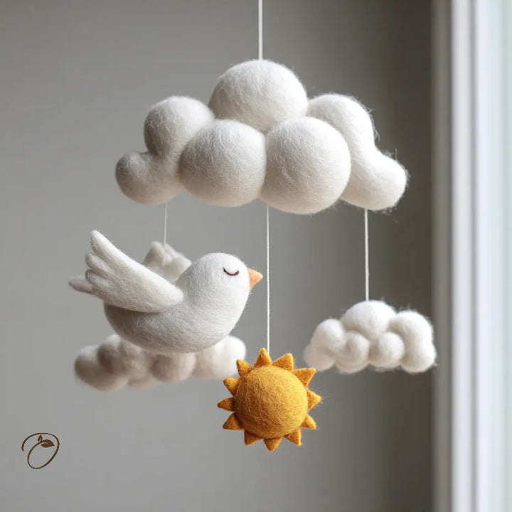 Felt cloud, bird, and sun mobile on a plain background