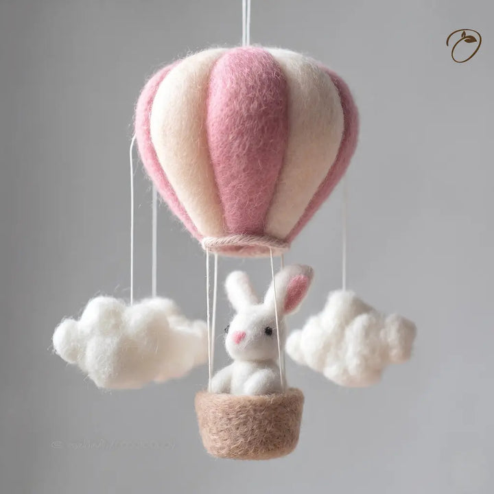 Felted toy hot air balloon with a bunny inside on a gray background