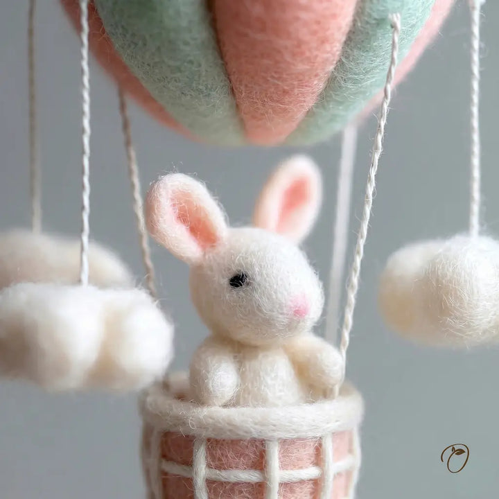 Felted rabbit in a hot air balloon with a soft focus background