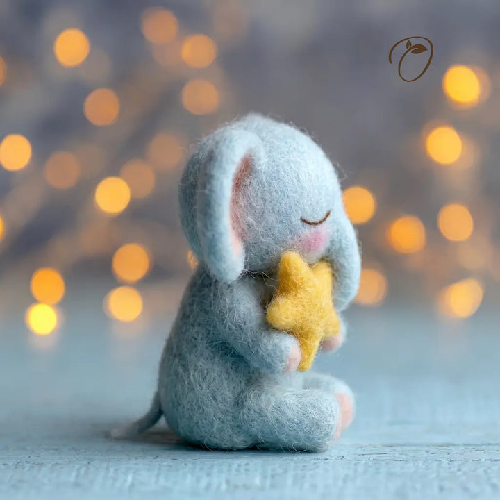 Felted elephant holding a yellow star against a blurred bokeh background
