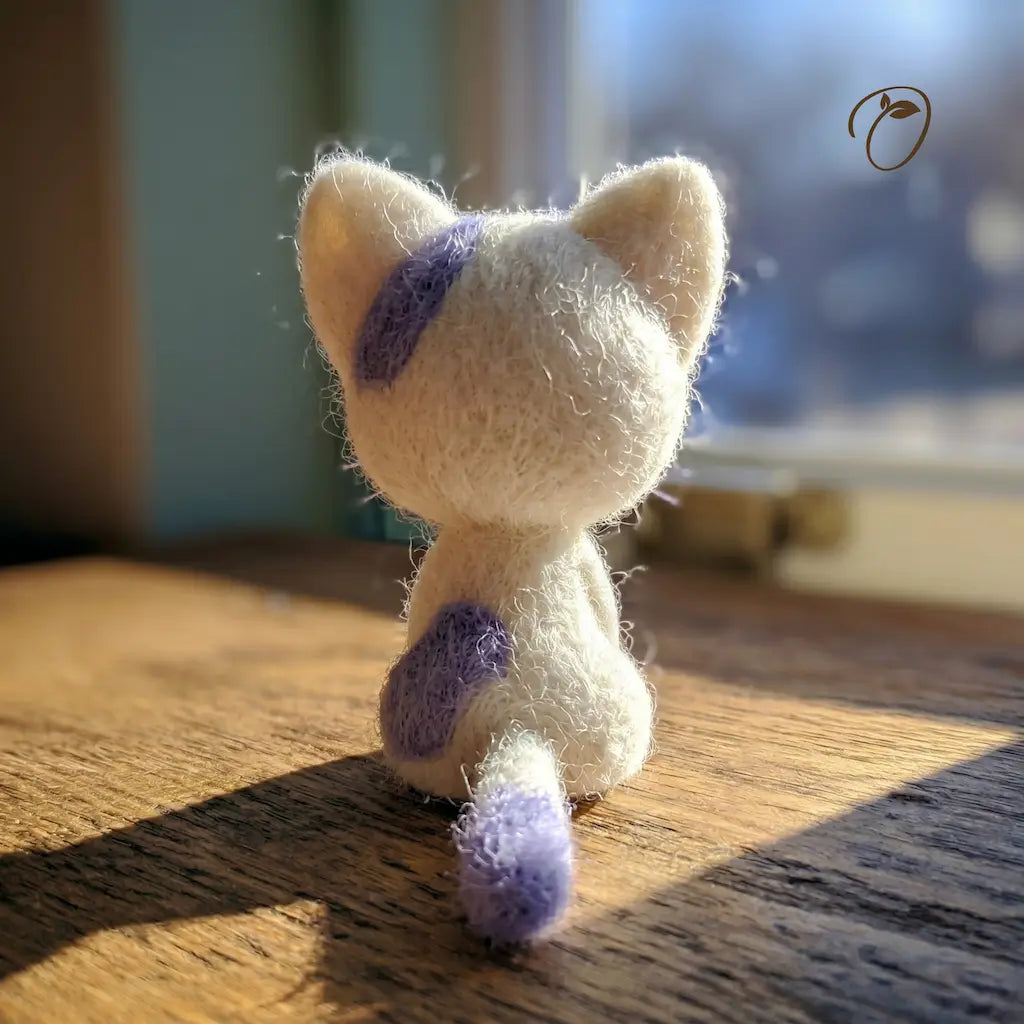 Small plush toy with purple accents on a wooden surface