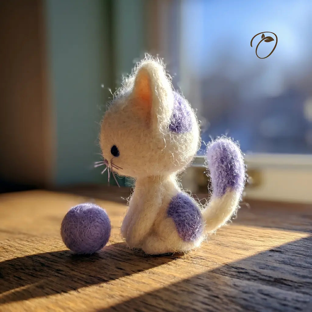 Small plush cat toy with purple spots on a wooden surface