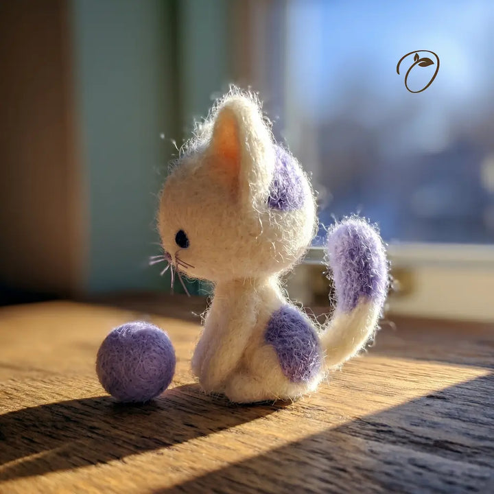 Small plush cat toy with purple spots on a wooden surface