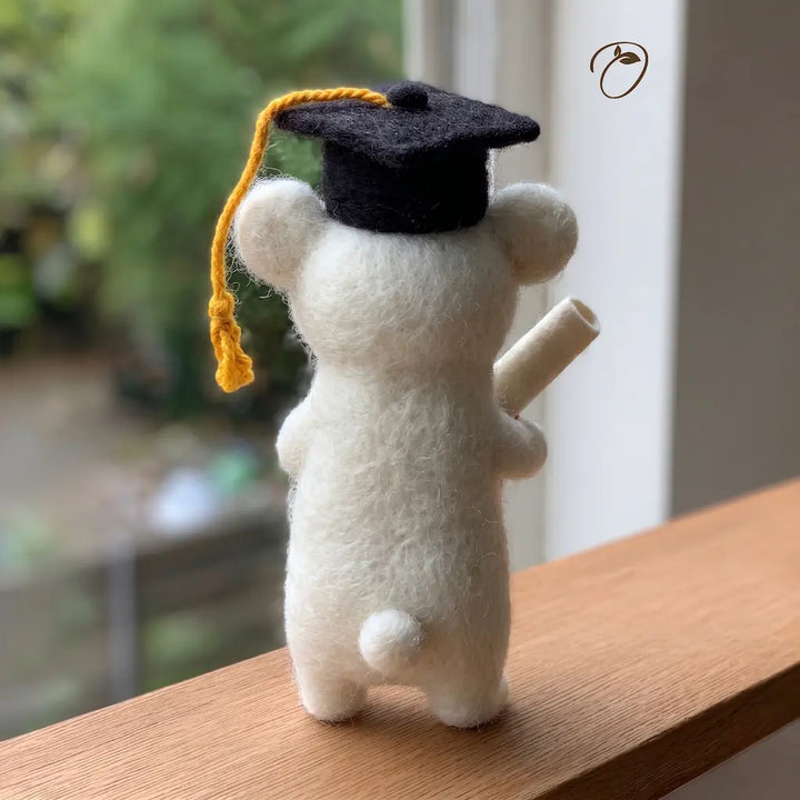 Graduation-themed plush toy on a wooden surface with a blurred background