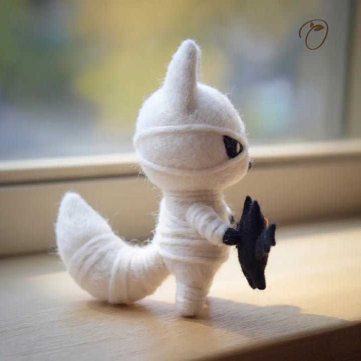 White plush toy with black accents on a wooden surface