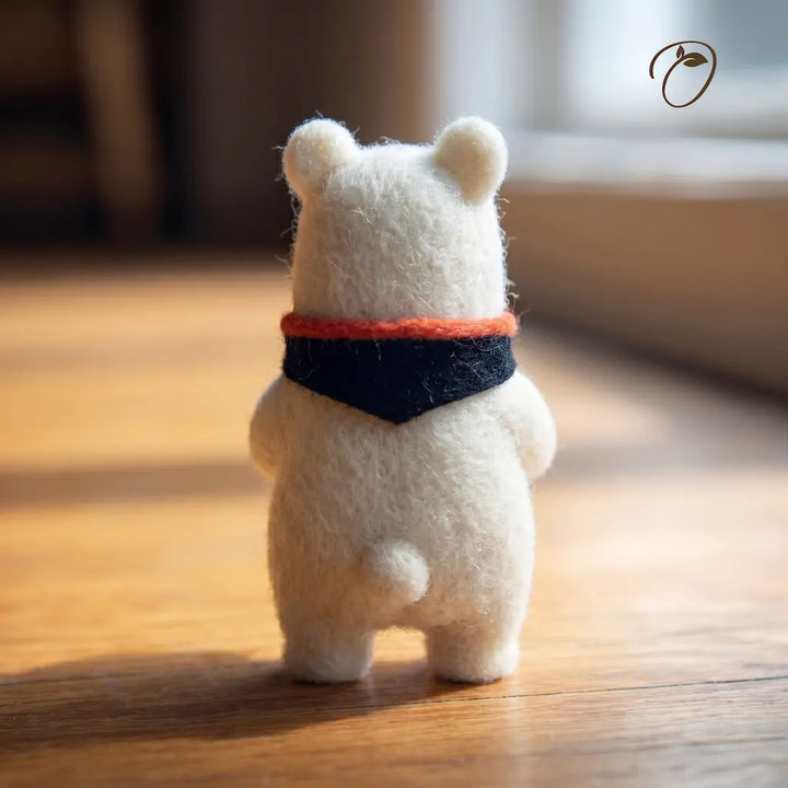 Small white bear figurine with a red and blue scarf on a wooden surface