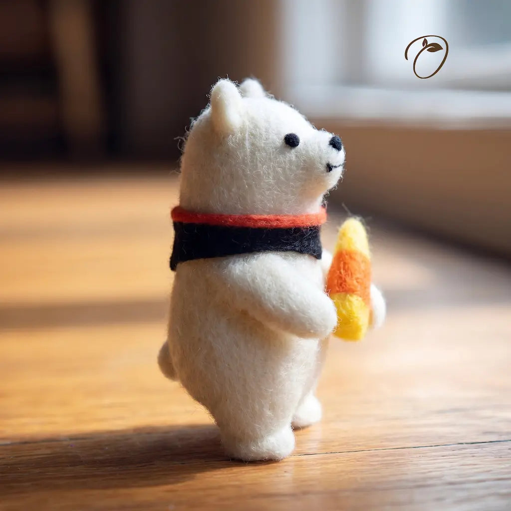 White bear figurine with a red scarf and candy corn on a wooden floor
