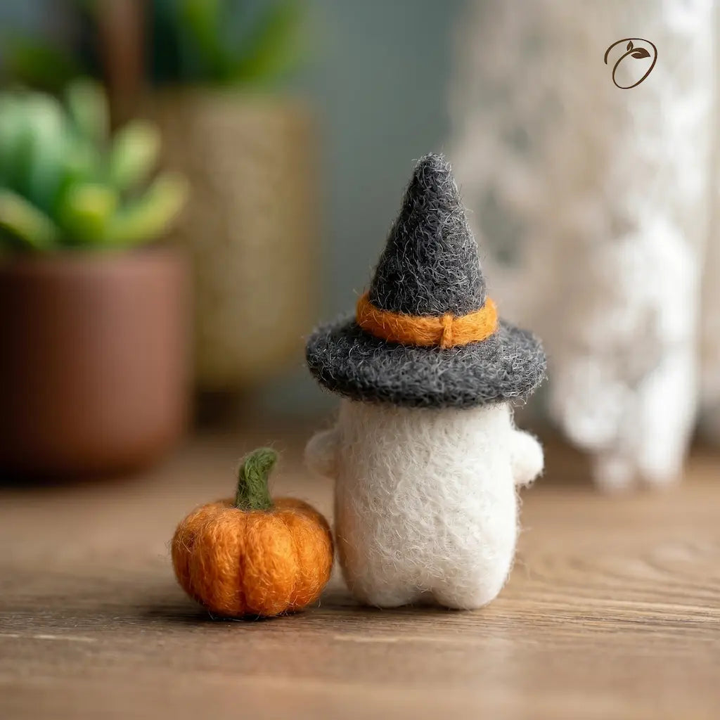 Small plush toy with a witch hat and pumpkin on a wooden surface