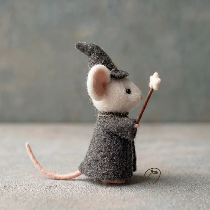Felted mouse figurine dressed as a wizard with a hat and staff on a neutral background