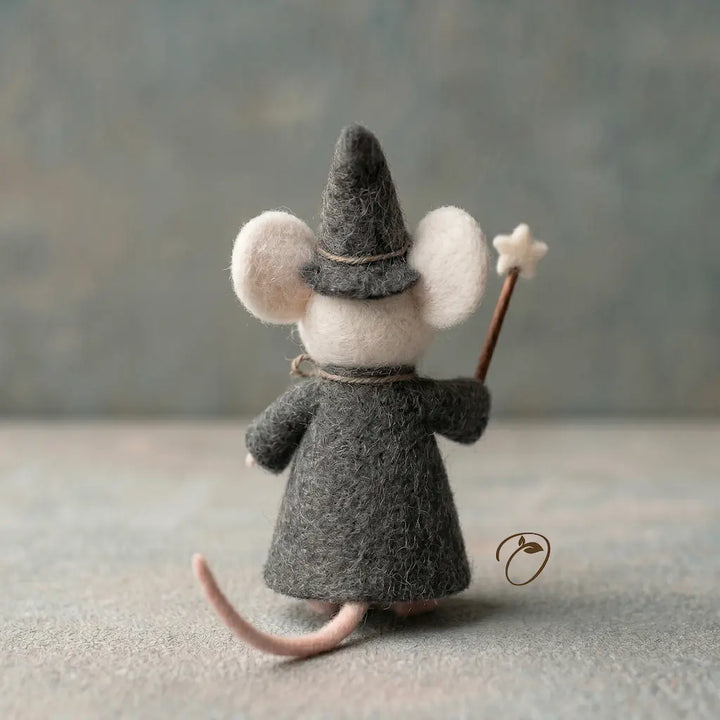 Felted mouse toy dressed as a wizard with a hat and staff on a neutral background