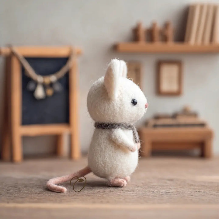 White plush mouse toy on a wooden floor with a blurred background