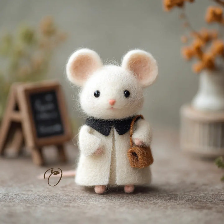 Felted mouse toy wearing a coat and holding a bag in a cozy setting