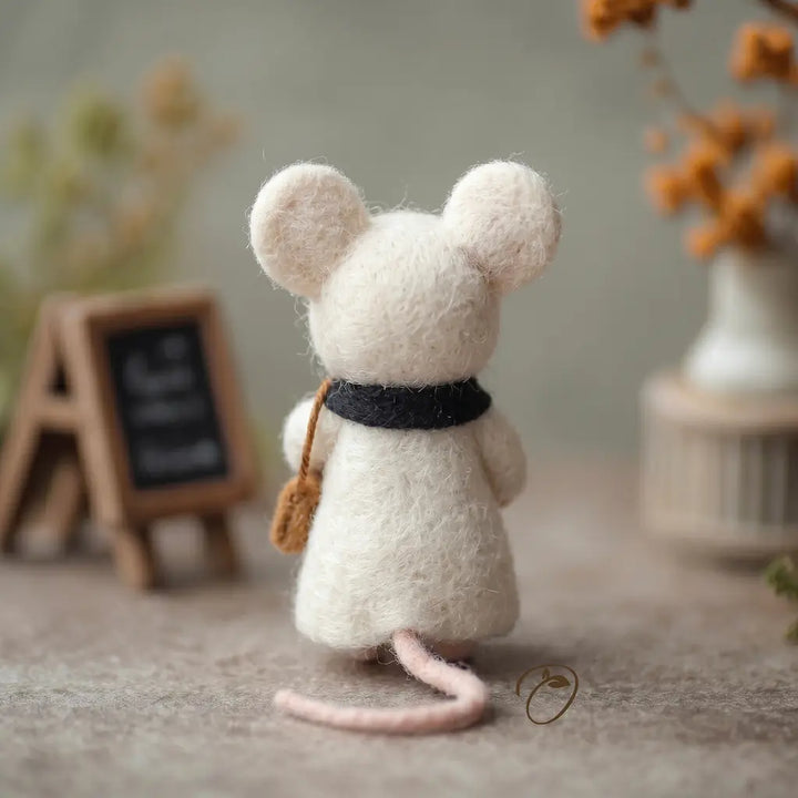 White felt mouse figurine with a black ribbon on a neutral background