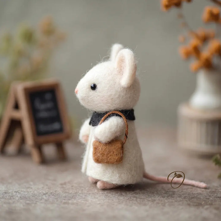 White mouse figurine with a brown bag in a decorative setting
