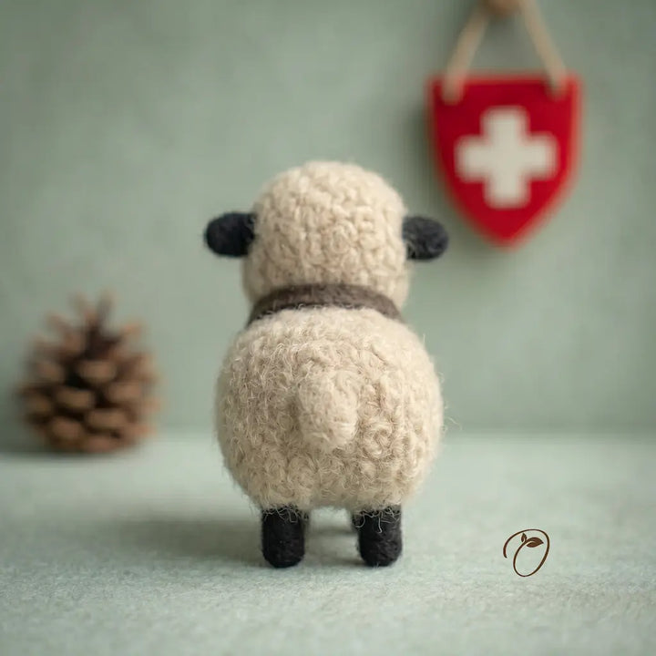 Small plush sheep toy with a red shield featuring a white cross on a light green background.