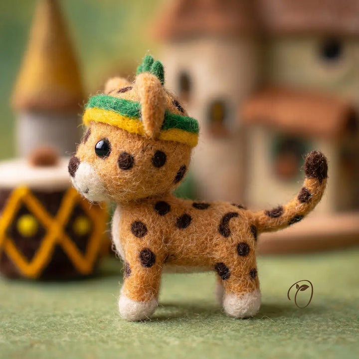Small plush toy cheetah wearing a hat in front of a blurred background with decorative elements.