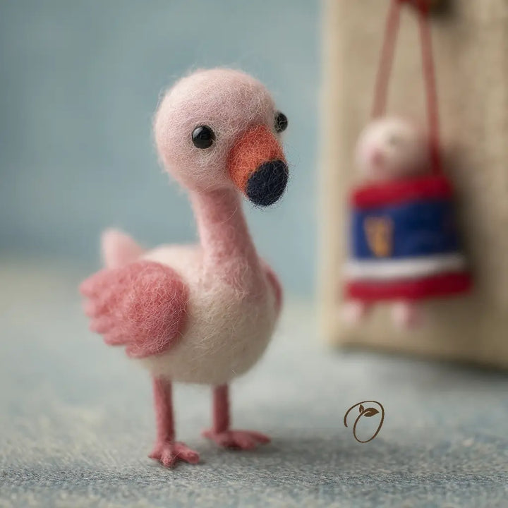 Pink felt flamingo toy on a textured surface with a blurred background