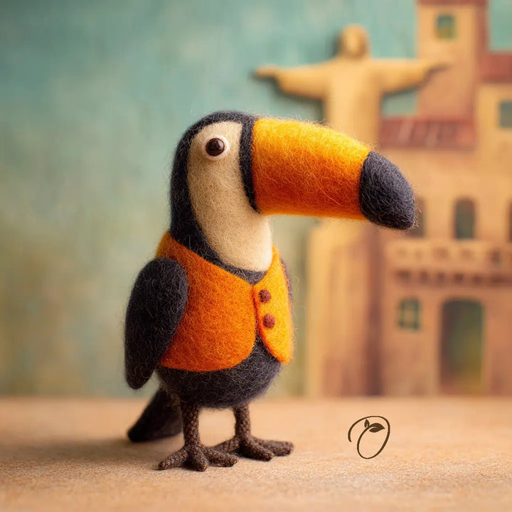 Felted toucan toy with an orange beak and chest, wearing a brown vest, against a textured background.