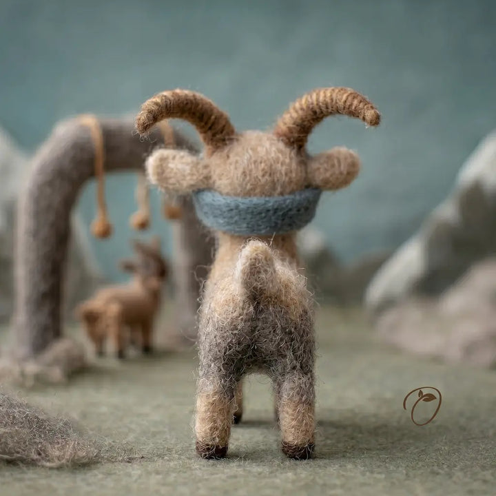 Felted animal figurine with a blue scarf in a natural setting