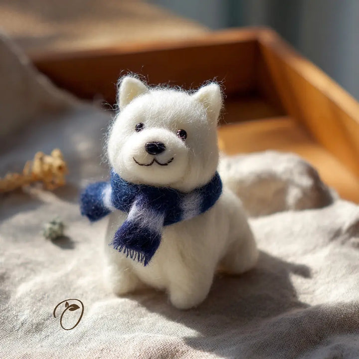 White plush dog toy with a blue scarf on a soft surface