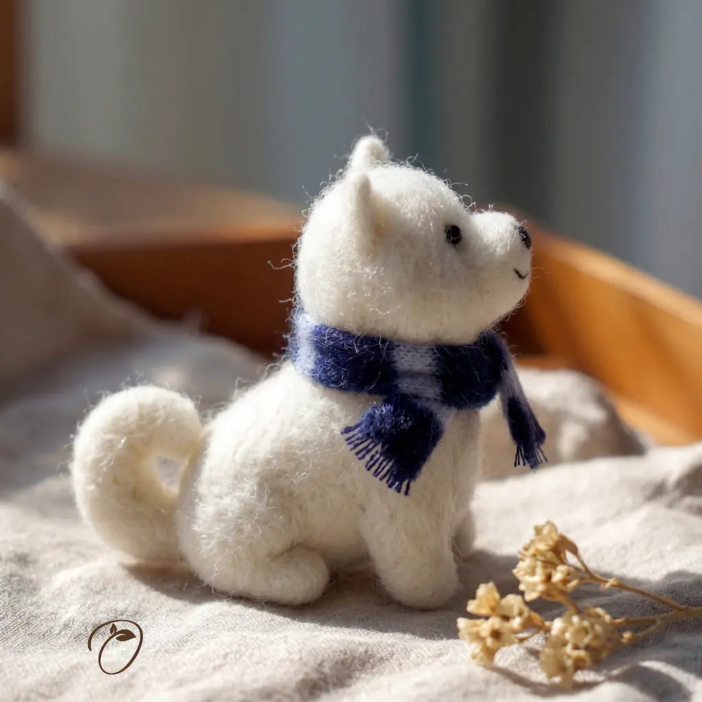 White plush dog toy with a blue scarf on a soft surface with a blurred background