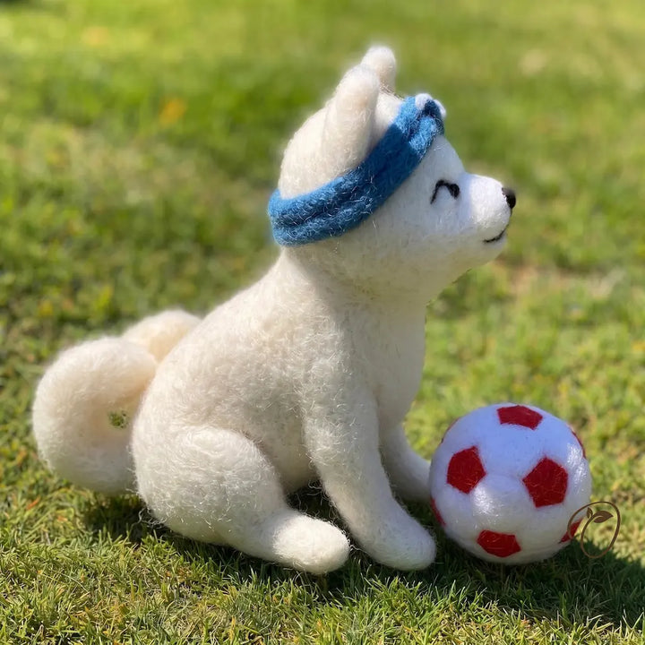 Plush toy dog with a blue bandana and soccer ball on grass