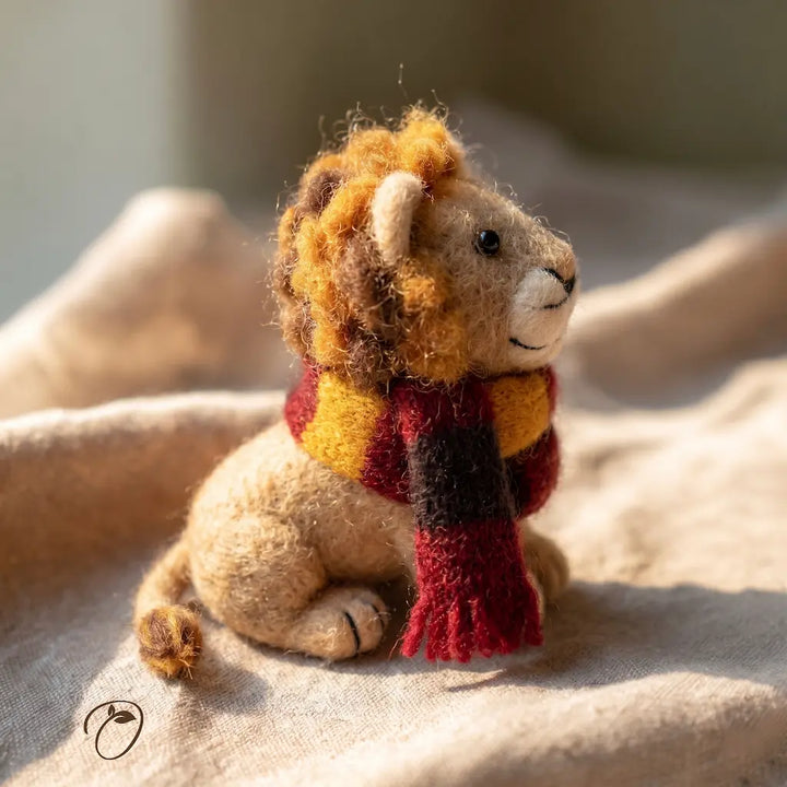 Small lion figurine wearing a red scarf on a soft surface