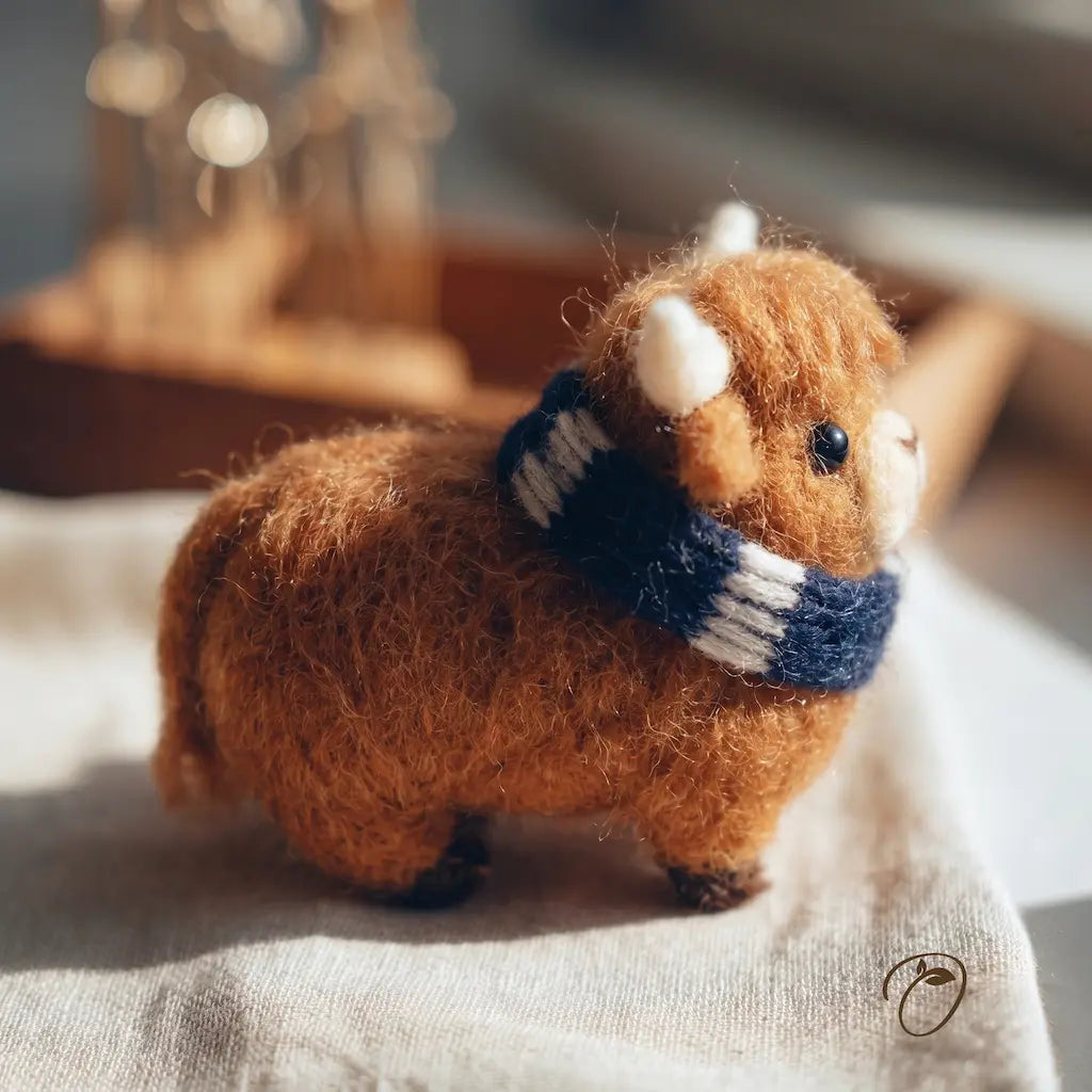 Small brown animal figurine wearing a blue and white scarf on a textured surface.