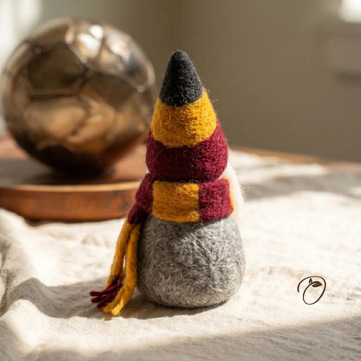 Small figurine with a pointed hat and scarf on a textured surface