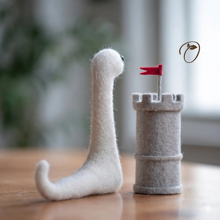 Felted toy snake with a castle and red flag on a wooden surface