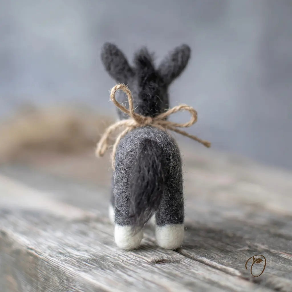 Small felted rabbit figurine with a bow on a wooden surface