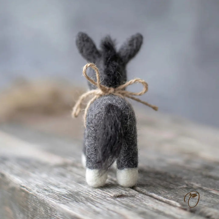Small felted rabbit figurine with a bow on a wooden surface