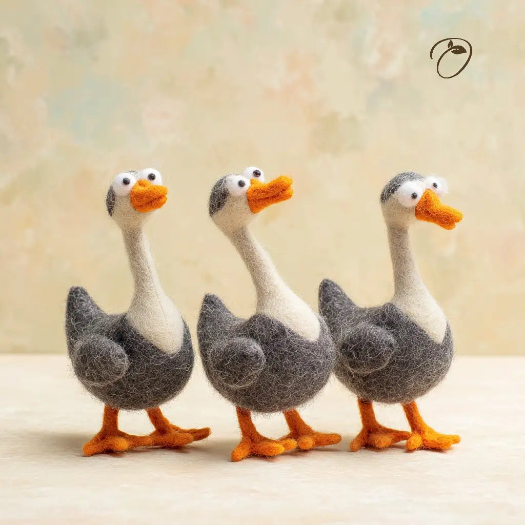 Three toy ducks with gray bodies, white faces, and orange beaks and feet on a light background.