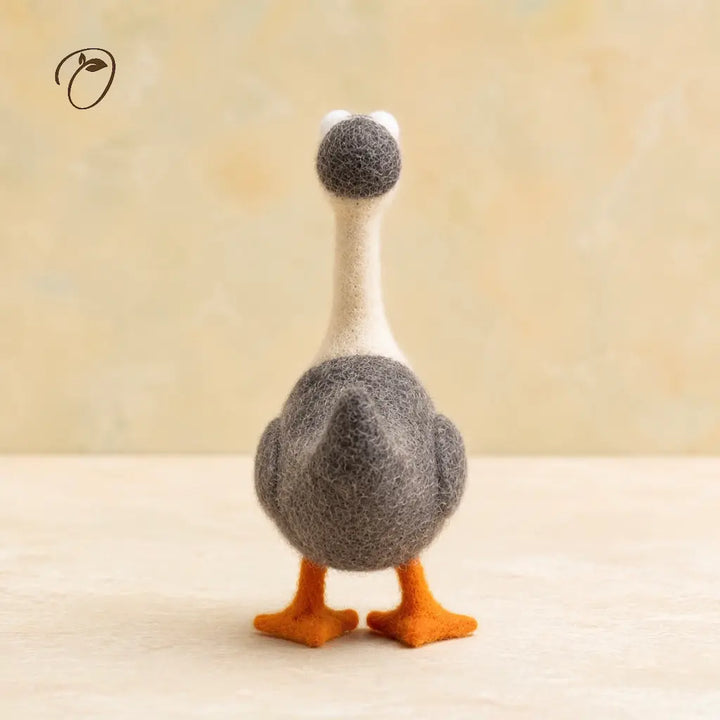 Stuffed toy goose with a fluffy gray head and orange feet on a beige background
