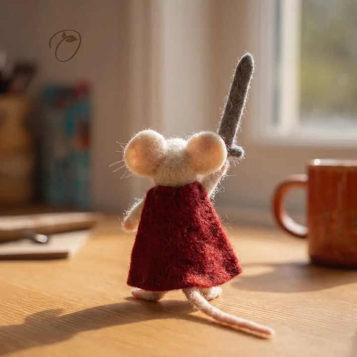Small plush mouse toy in a red dress on a wooden surface with a blurred background