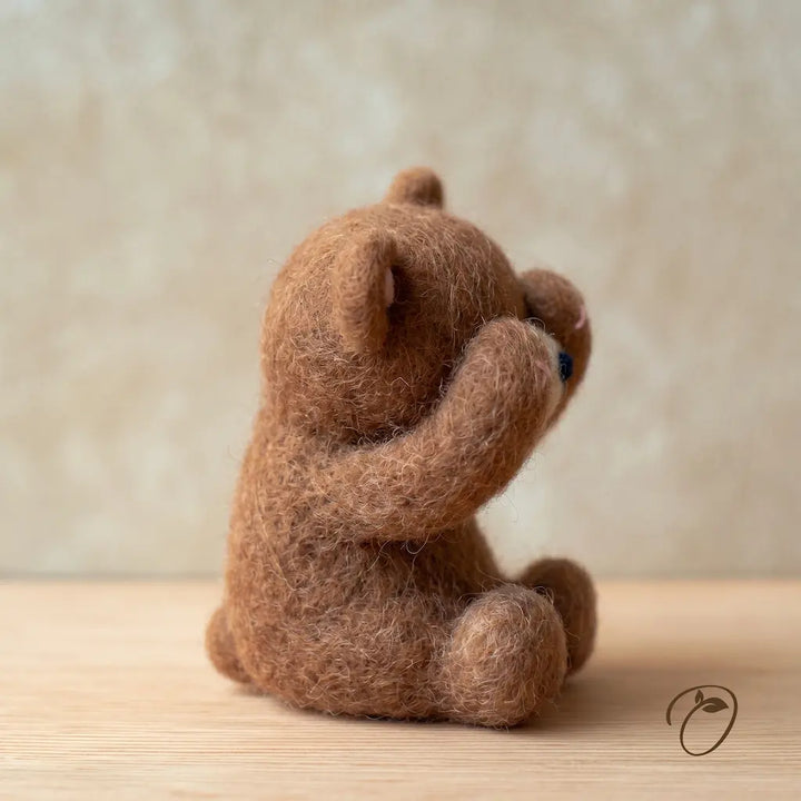 Brown teddy bear sitting on a wooden surface with a blurred beige background