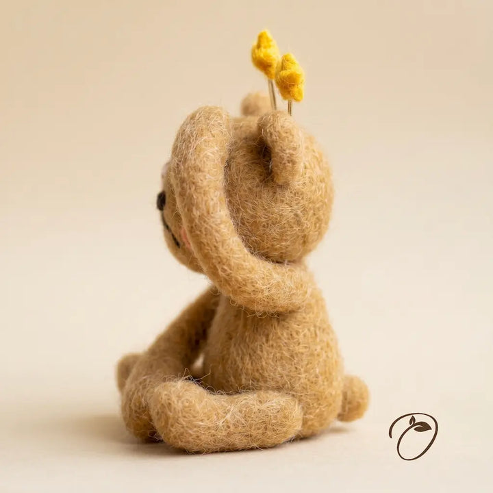 Small brown teddy bear with a yellow flower on a beige background
