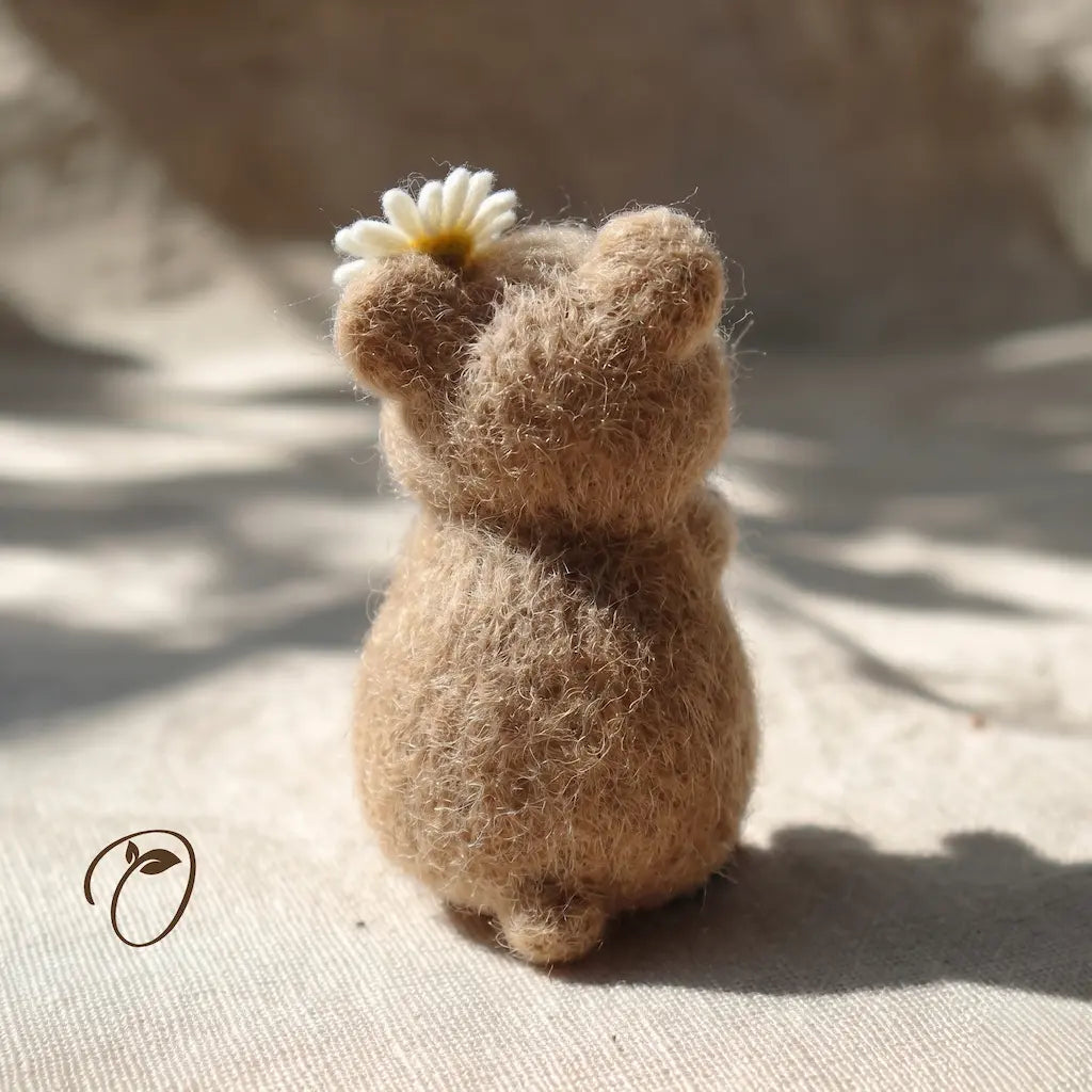 Small brown figurine holding a white flower on a textured surface