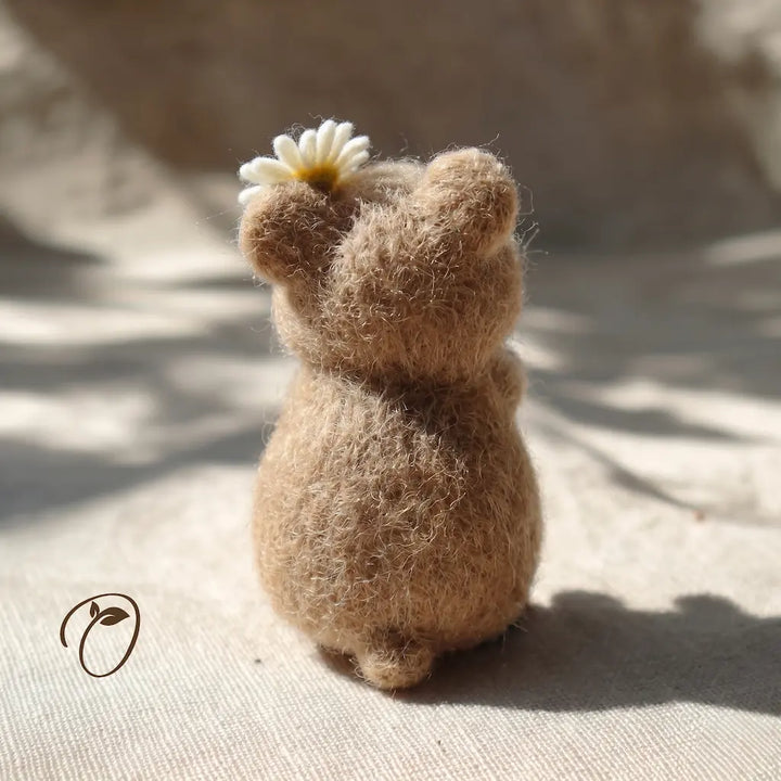 Small brown figurine holding a white flower on a textured surface