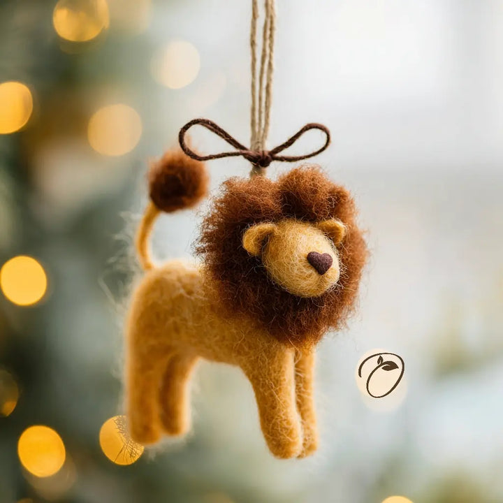 Felt lion ornament hanging against a blurred festive background with lights.