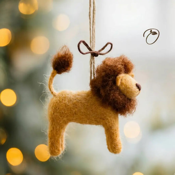 Felted lion ornament hanging against a blurred festive background with lights.