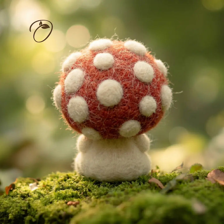 Felted mushroom toy on a grassy surface with a blurred green background