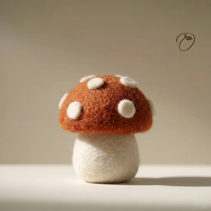 Felted mushroom toy on a neutral background